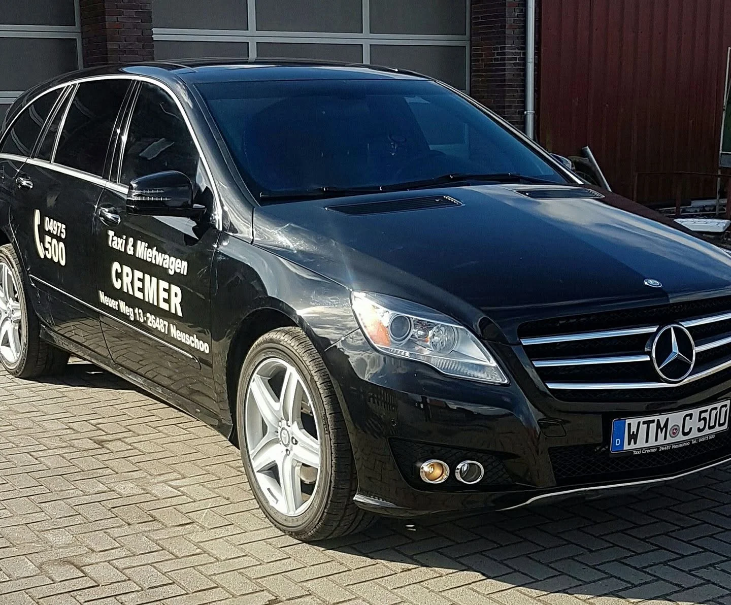 Das schwarze Mercedes-Taxi von Taxi Cremer mit der Telefonnummer 04975 500 an der Tür